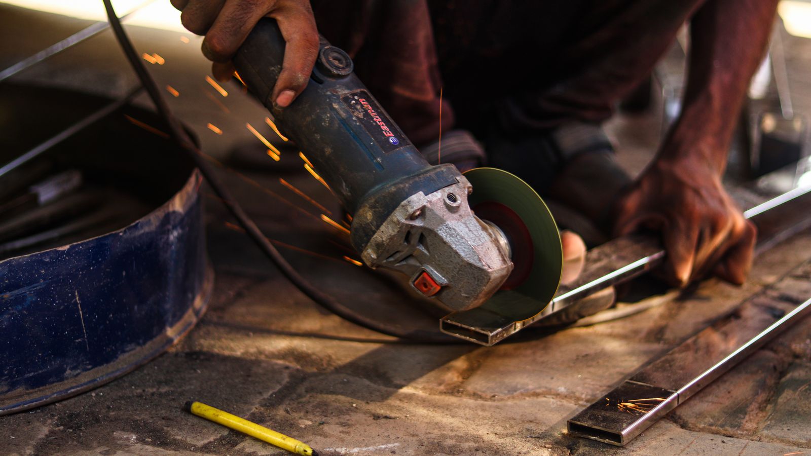 Close-up of a worker cutting metal with an angle grinder as sparks fly